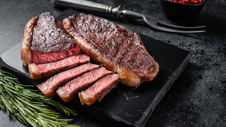cooked steak sliced up on cutting board