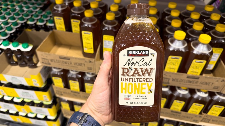 a hand holds a bottle of costco honey