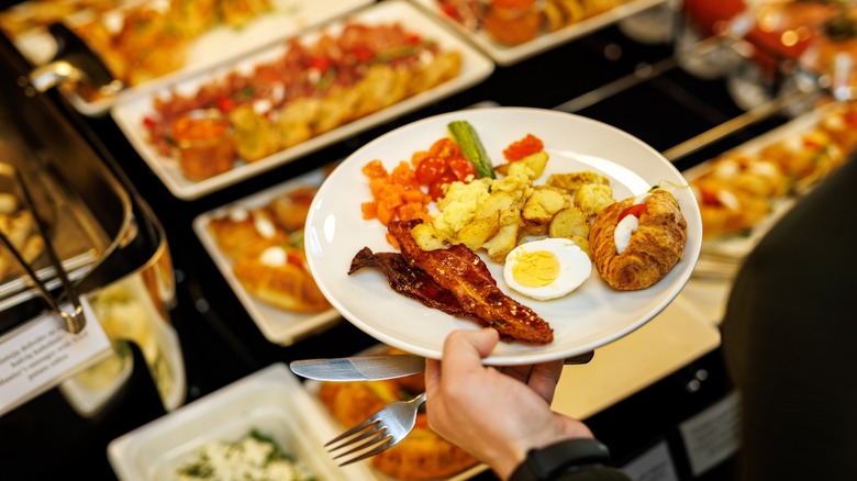 a person holds a plate at a breakfast buffet