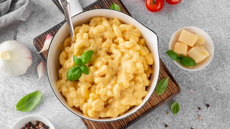 Mac and cheese in a white pot garnished with basil.
