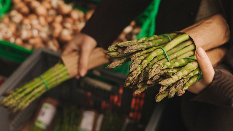 Person buying asparagus in grocery store