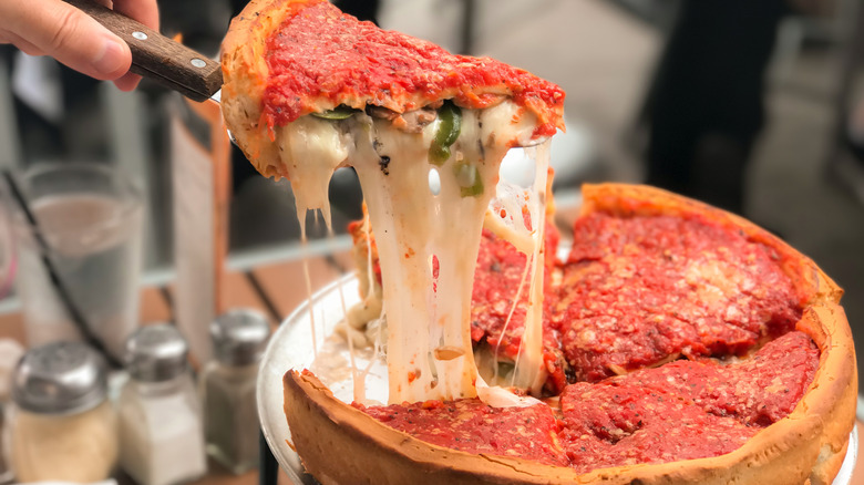 Person taking slice out of a deep-dish pizza at generic restaurant.