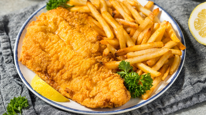 Fried catfish on a white plate with french fries