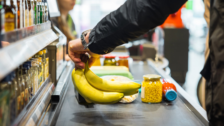 man laying things on grocery conveyer belt