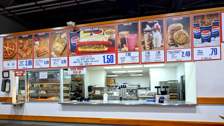 A Costco food court with menu signs and order windows.