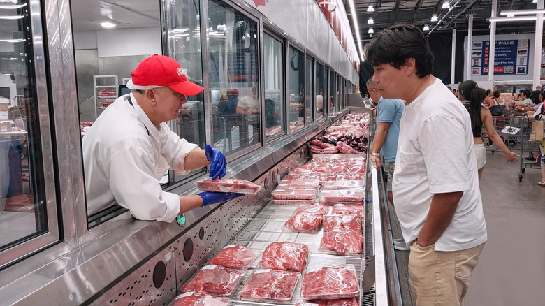 A Costco employee helps a customer in the meat department