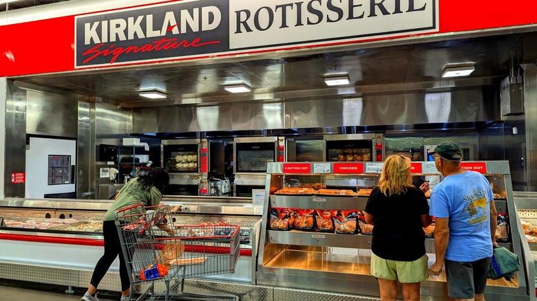 costco customers in front of the rotisserie chicken display