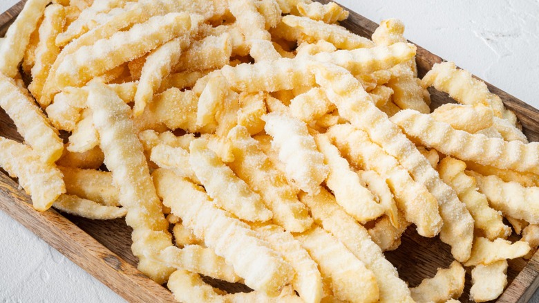 frozen french fries on wooden tray