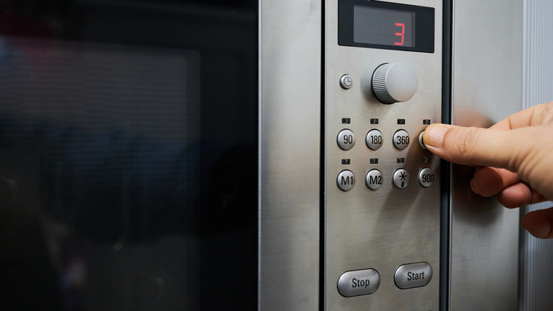 Up close shot of a hand setting a microwave
