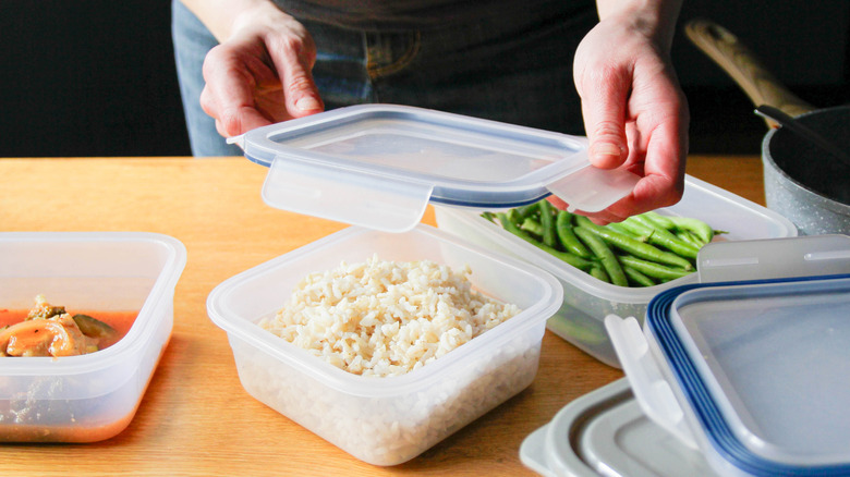 Someone putting various leftovers, including rice, into plastic containers