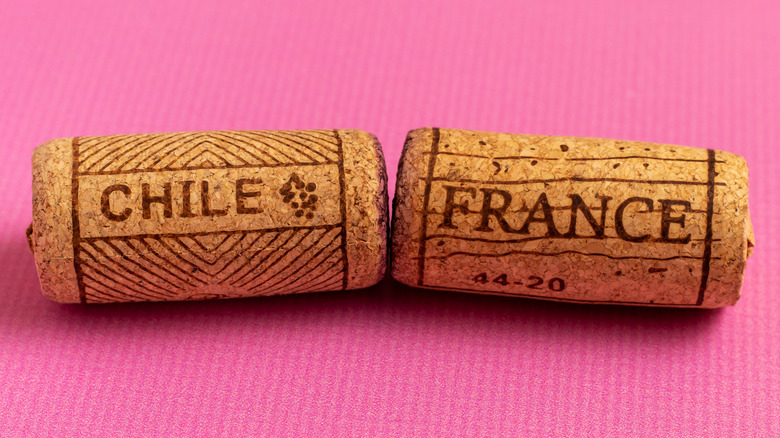 two wine corks bearing the words Chile and France against a pink background