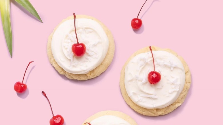 crumbl piña colada cookies on pink background with cherries