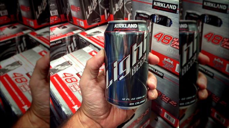 A hand holds a can of Kirkland Signature Light Beer