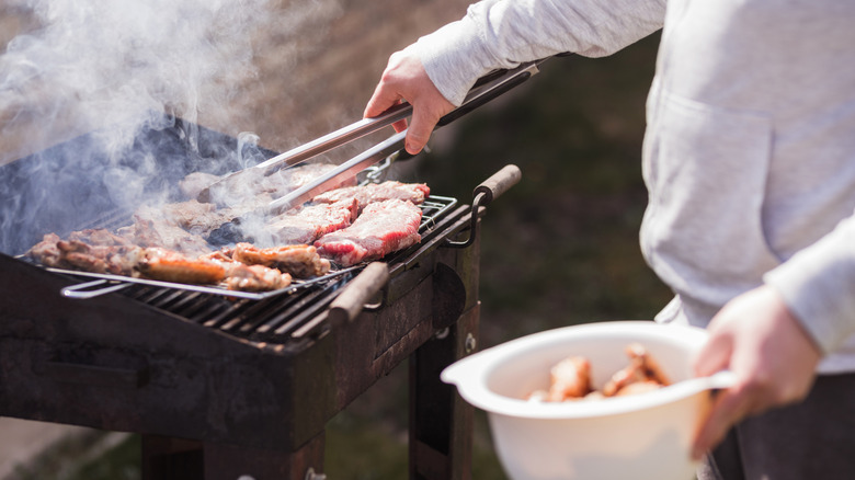 Closeup person grilling meat.