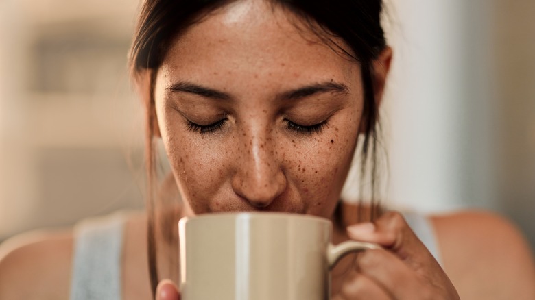 woman with freckles drinks cup of coffee