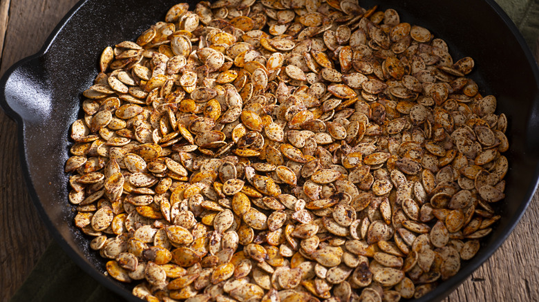 Seasoned pumpkin seeds roasting in cast iron pan