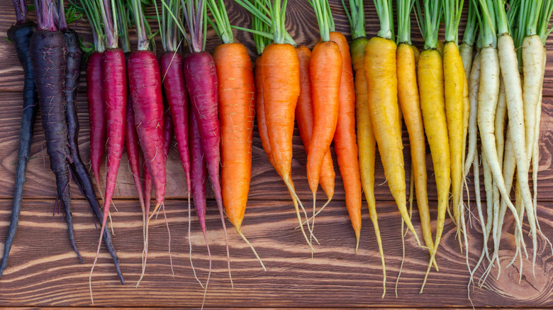 Yellow, red and orange carrots on a wooden board