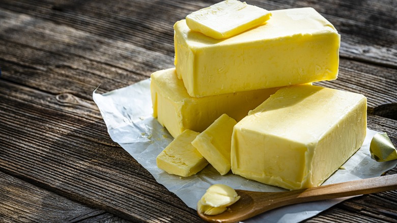 Butter on wrapper with wood spoon nearby on wood table