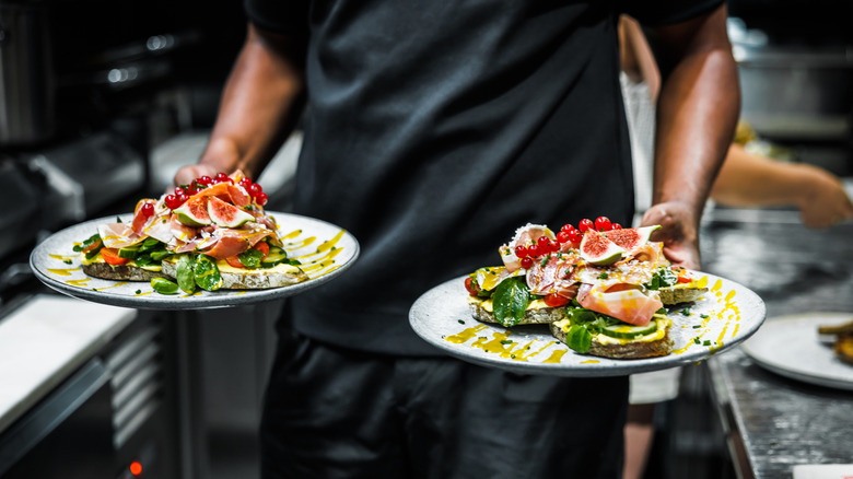 Server carrying two beautiful salads.