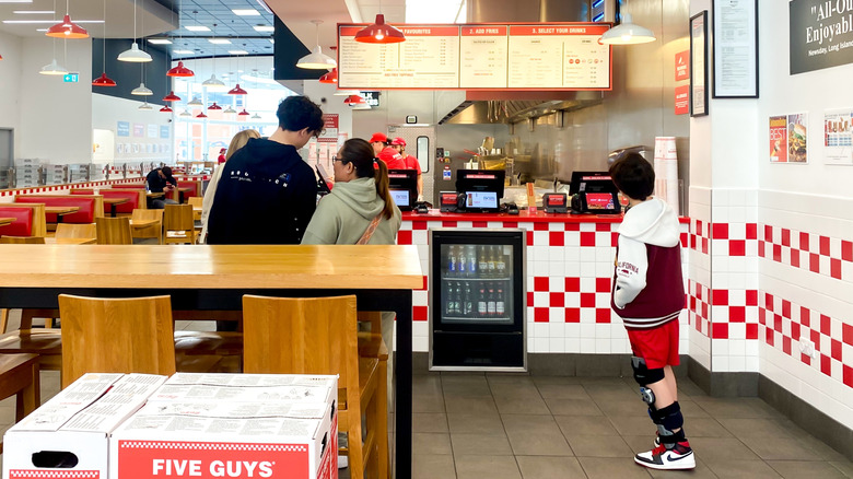 A family ready to order food in a Five Guys restaurant