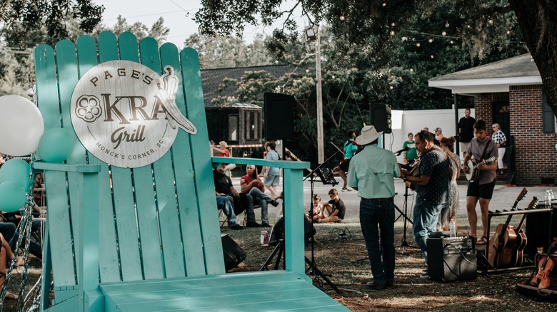 Blue chair with Page's Okra Grill sign, band in background