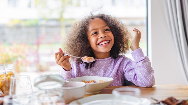 happy child eats cereal and milk