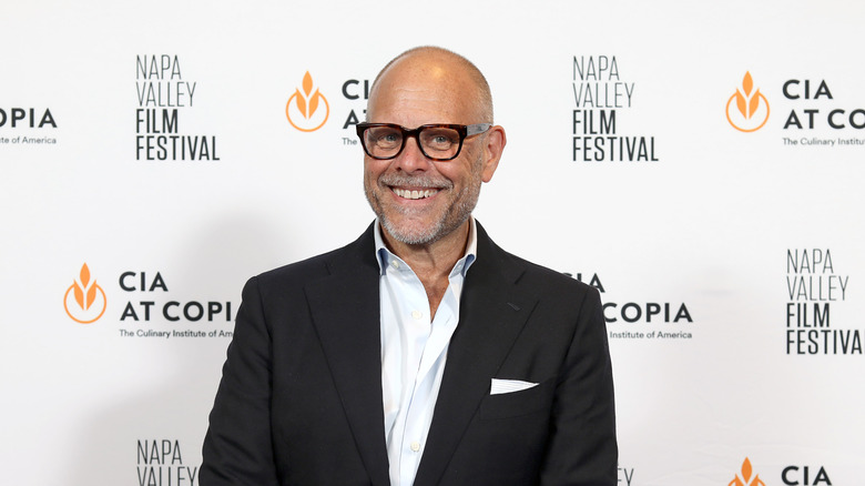 Alton Brown smiling while wearing dark suit jacket