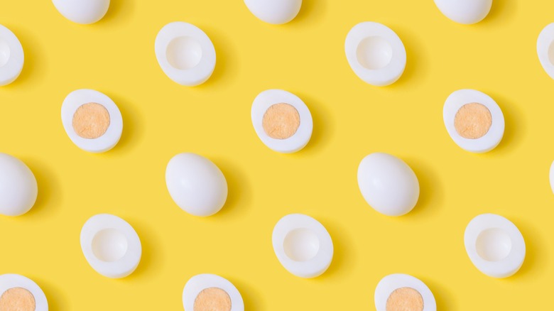 whole and halved hard-boiled eggs on yellow background