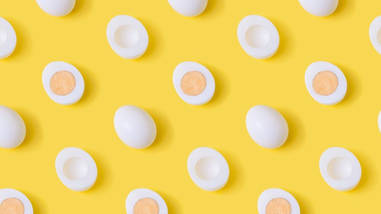 whole and halved hard-boiled eggs on yellow background