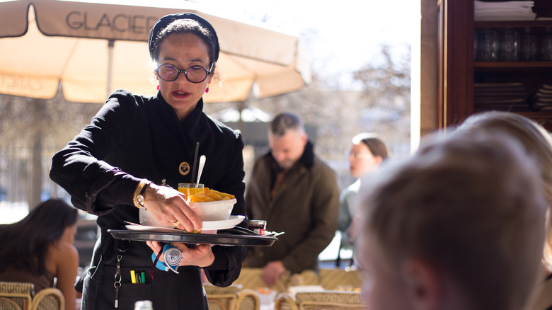 A waitress at a sidewalk cafe in the Marais
