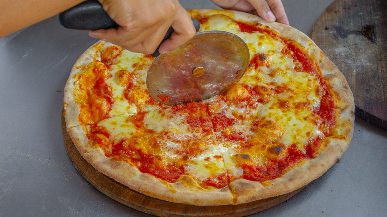 closeup of a cheese pizza being cut with a pizza cutter