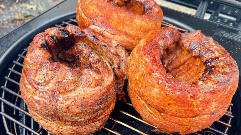 Three rolled ribs cooking on a small grill
