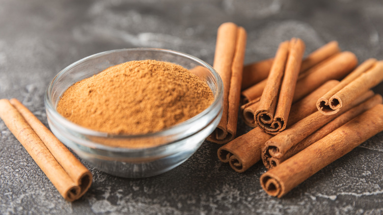Cinnamon sticks with ground cinnamon in a glass bowl