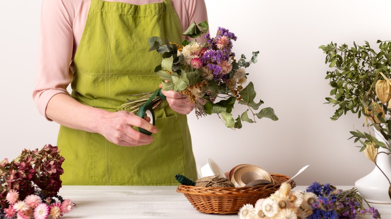 florist in apron arranges flowers