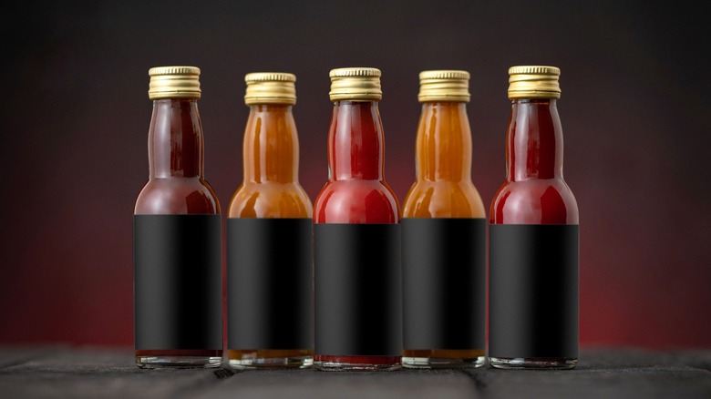 Various hot sauces with blank labels on table