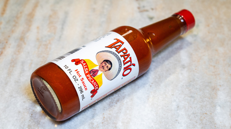 Bottle of Tapatio hot sauce laying on side on table