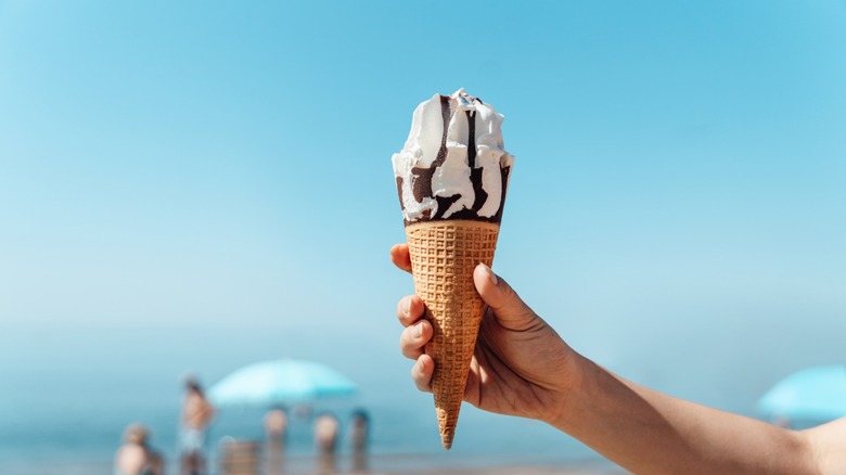 hand holds an ice cream cone at the beach