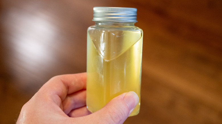 A hand holds a jar of beef tallow