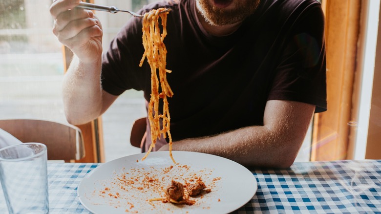 eating spaghetti at a table with checkered tablecloth