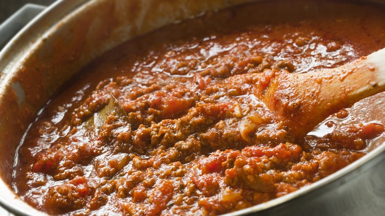 skillet of bolognese sauce with wooden spoon
