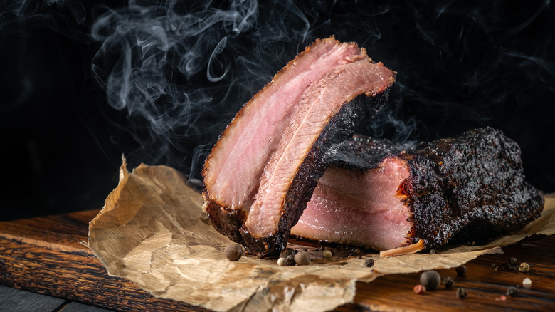 Smoked beef brisket on wood board with smoke trails