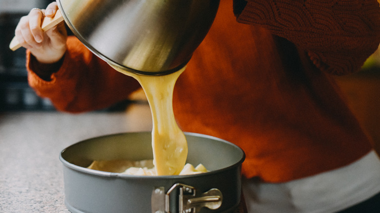 Closeup of person pouring cake batter into springform pan.