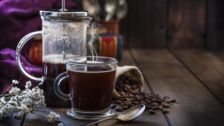 French press with coffee and whole beans