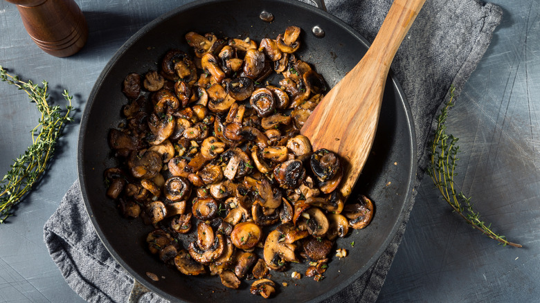 Pan of butter sauteed mushrooms with sprigs of fresh thyme.