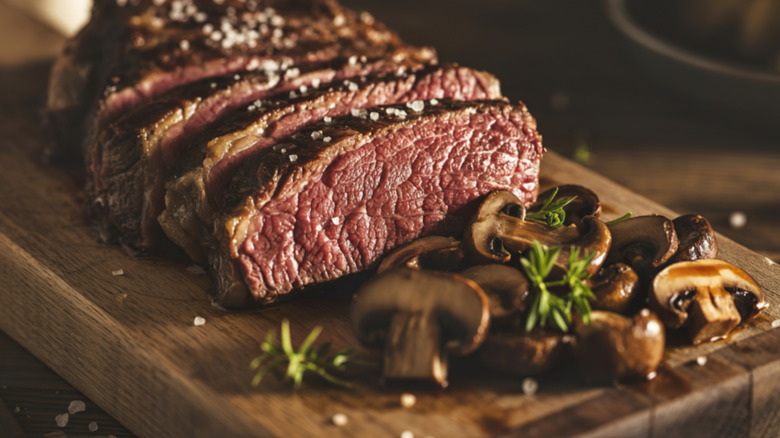 Sliced rare ribeye steak with sauteed mushrooms.