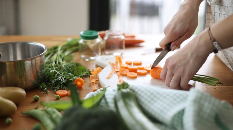 hands cut up vegetables in a kitchen