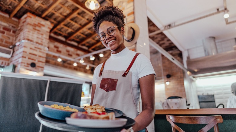 smiling server carries tray of yummy food