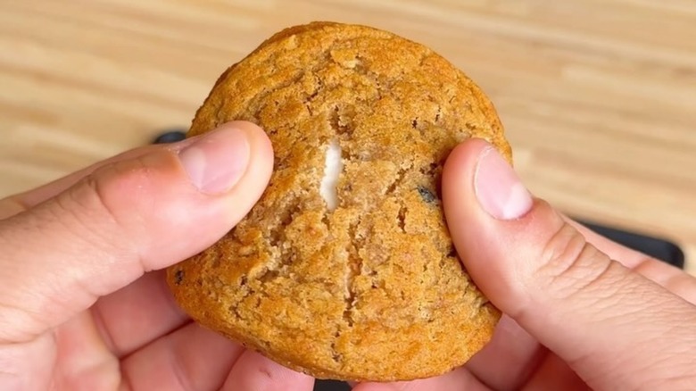 Hands breaking open a Little Debbie Oatmeal Creme Pie, closeup.