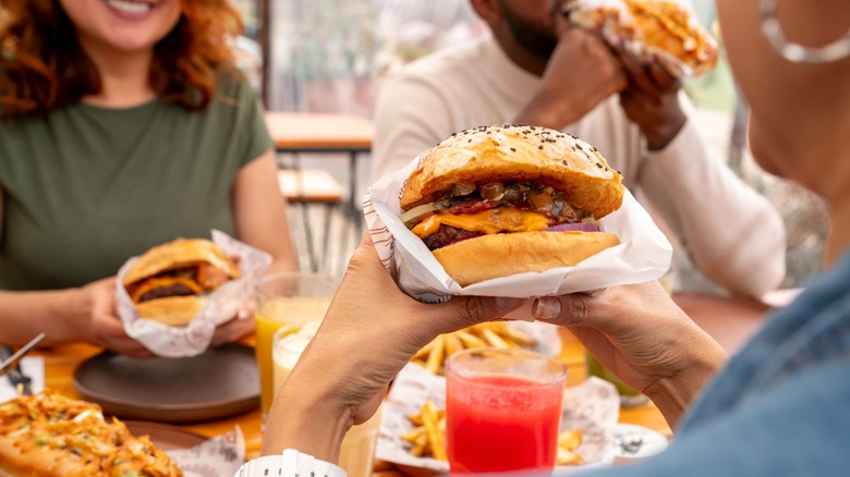 customers hold burgers at a restaurant