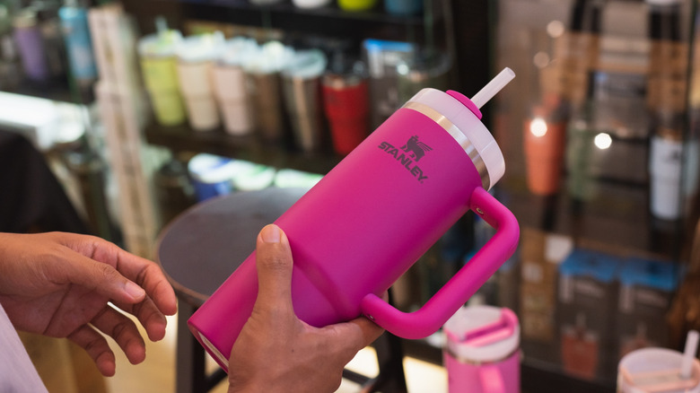 Closeup hand holding bright pink Stanley Quencher mug.